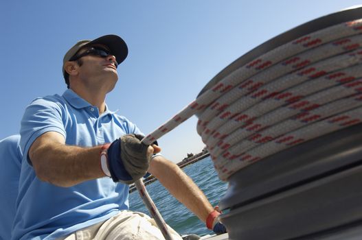 Sailor adjusting rope on boat