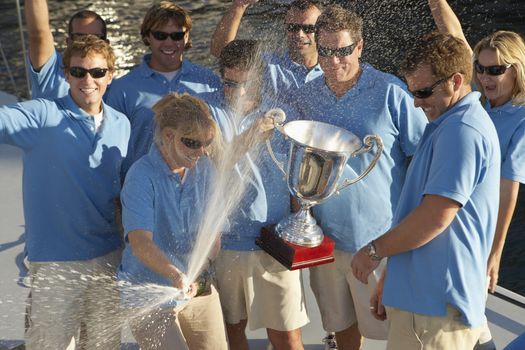 Sailing team celebrating with trophy on boat