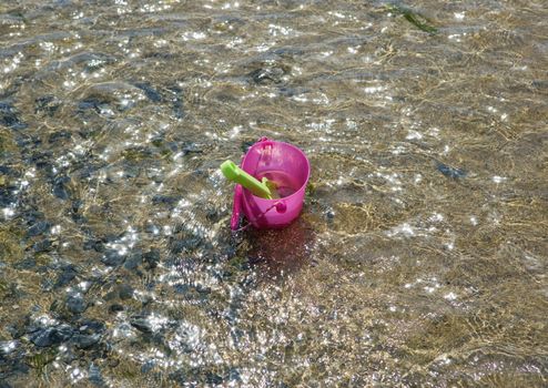 Toy bucket and spade in shallow water