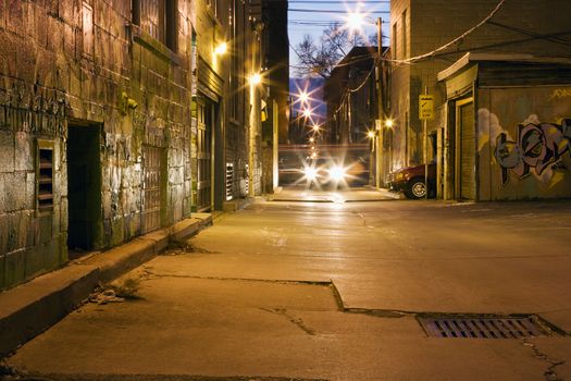 Car head lights in alleyway at dusk