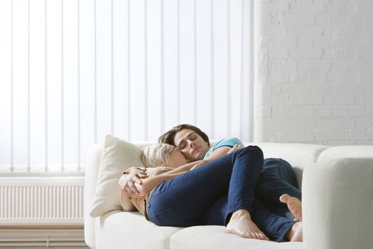 Young couple napping on sofa embraced close-up