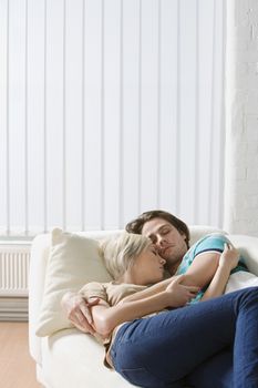 Young couple napping on sofa embraced close-up