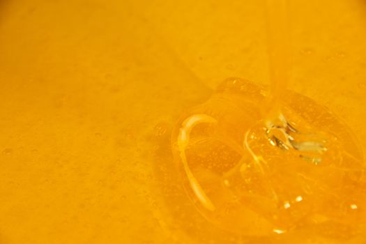 Close up pouring fresh fluid honey in bowl