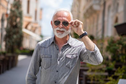 Old rich man with sun glasses and beard on street portrait