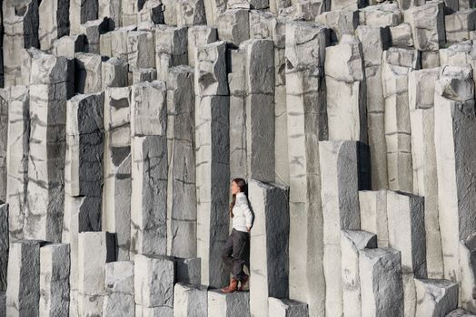Iceland tourist at beach sitting on basalt columns Reynisfjara black sand beach