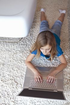 Young girl with laptop lying on rug