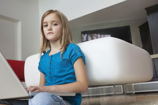 Portrait of young girl with laptop sitting in house