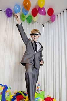 Cheerful young boy with raised fist in birthday party