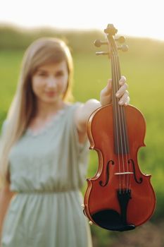 Violin in the hands of a young female violinist in the sunset light. 
