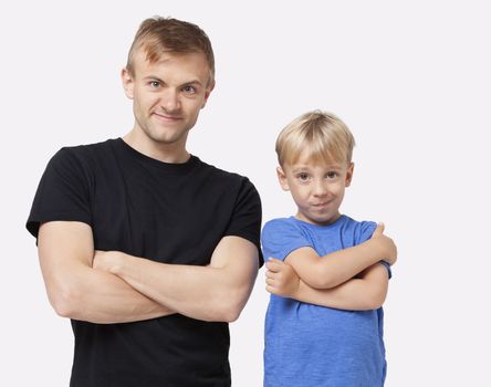 Portrait of happy father and son in casuals with arms crossed over white background