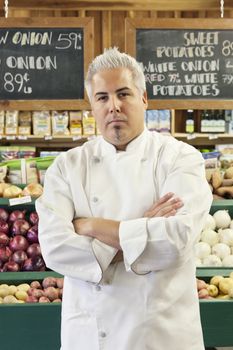 Portrait of a confident chef with arms crossed in market