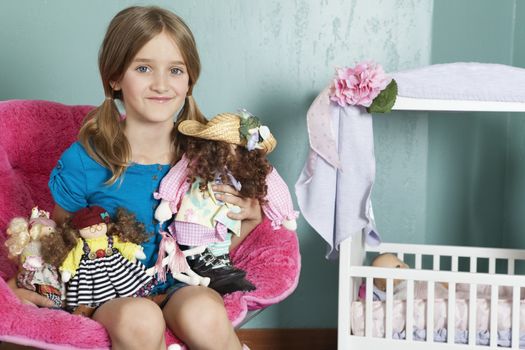Portrait of a little girl with stuffed toys sitting on chair by doll's crib