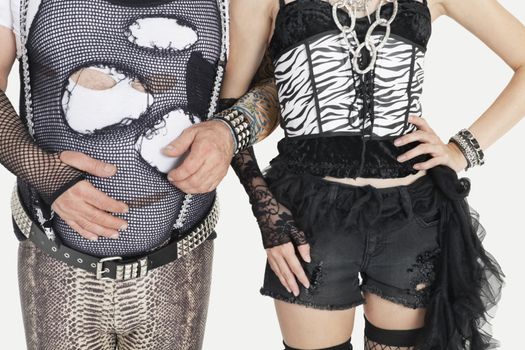 Midsection of punk man and woman standing with arm in arm