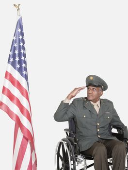 Senior male US military officer saluting American flag over gray background