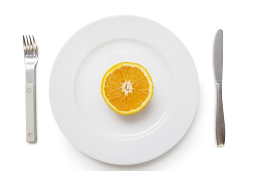 Cross section of an orange in plate with fork and knife over white background