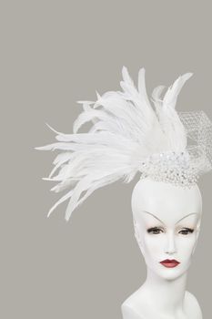 Feather fascinator on mannequin against gray background