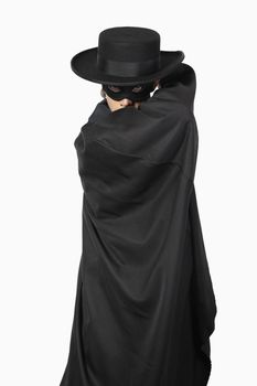 Portrait of young man dressed as Zorro over gray background