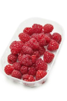Fresh raspberries in a container against white background