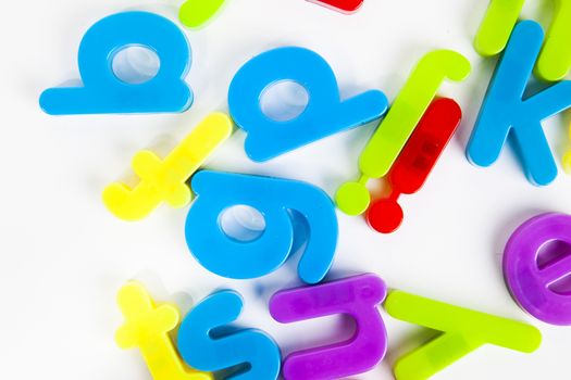 Close-up view of disordered alphabet magnets on white background