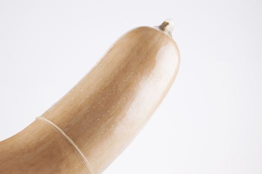 Close-up of condom on butternut pumpkin over white background