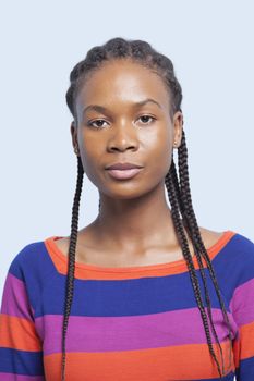 Portrait of serious young woman with braided hair against light blue background