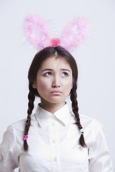 Contemplative Asian woman with bunny ears against white background