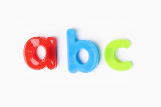 Colorful alphabet magnets spell 'a b c' over white background