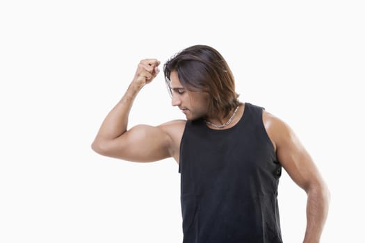Young Asian man flexing muscles over white background