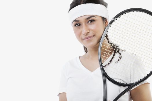 Portrait of young Asian woman with tennis racket against white background