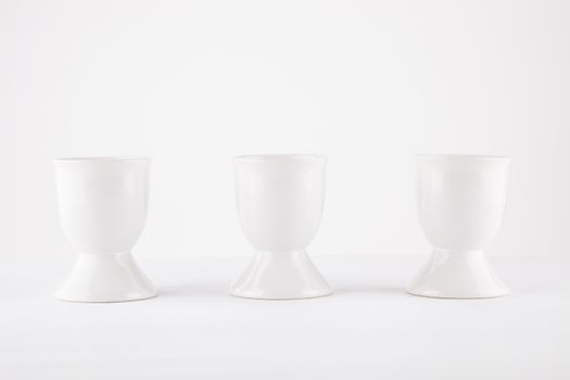 Three empty egg cups side by side over white background