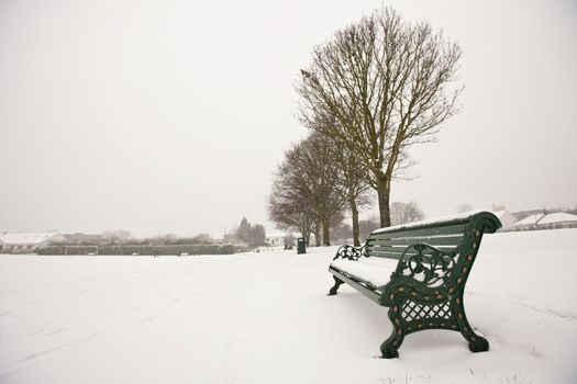 Park bench and park covered in snow
