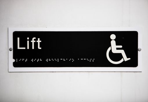 Close-up of handicapped elevator sign on wall