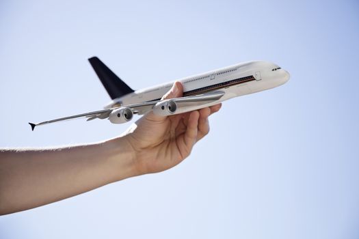 Close-up of hand flying toy airplane against clear sky