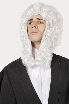 Young man dressed as judge against gray background