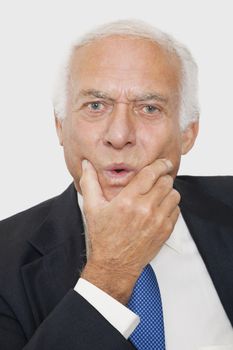 Portrait of suspicious elderly businessman against white background