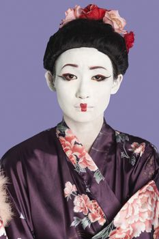Portrait of Japanese woman in kimono with painted face against purple background