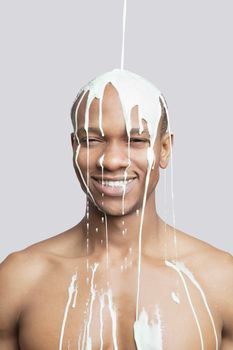 Paint falling on shirtless young Hispanic man's head against gray background