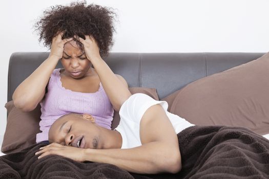 Young woman having headache while man sleeping on her lap in bed