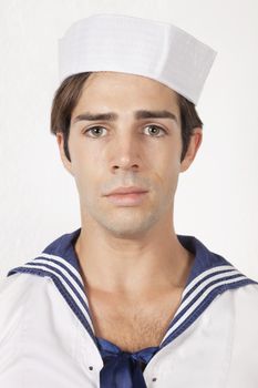 Portrait of sad young man in sailor's uniform against gray background
