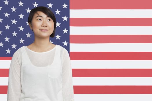 Thoughtful Asian woman looking away against American flag