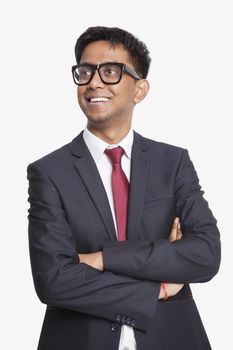 Young Asian businessman with arms crossed day dreaming against white background