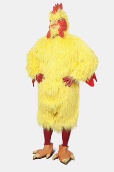 Young man in chicken suit standing with hands on hips against gray background