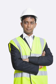 Portrait of confident Asian architect wearing reflective vest against white background