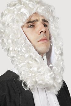 Young man dressed as judge against gray background