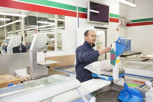 Male worker weighing products in grocery store
