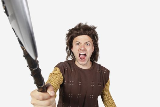 Portrait of angry man in caveman costume holding axe against gray background
