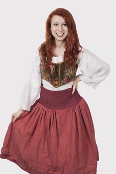 Portrait of young woman in old-fashioned costume standing against gray background