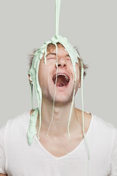 Paint falling on young Caucasian man against gray background