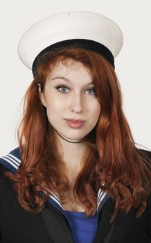 Portrait of young woman in sailor's uniform against gray background