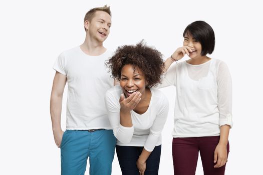 Young multi-ethnic friends in casuals laughing over white background